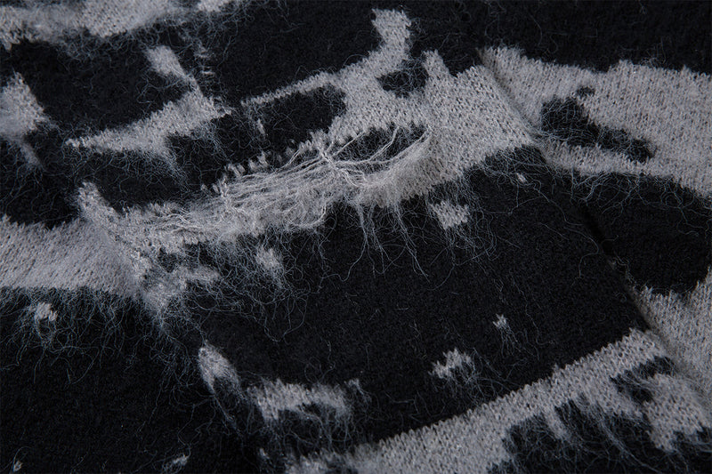 Close-up of distressed jacquard knit fabric showing loose gray fibers and irregular black patterning