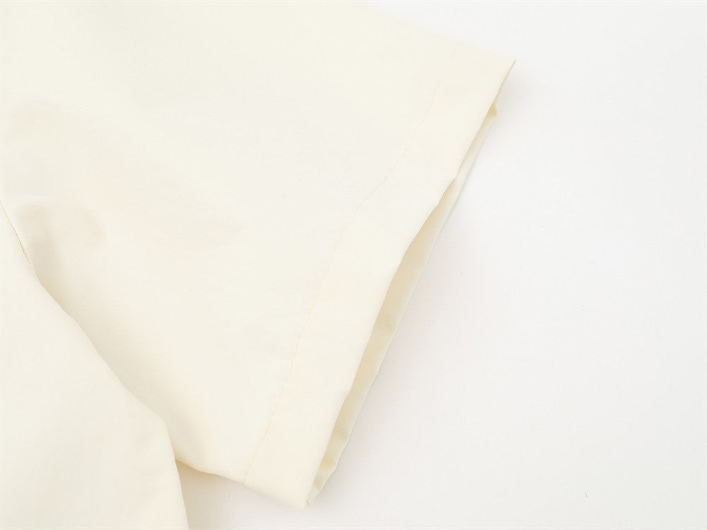 Cream shirt sleeve close-up with folded cuff and clean hem stitching
