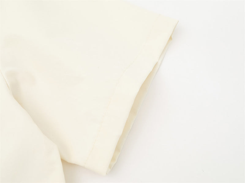 Cream shirt sleeve close-up with folded cuff and clean hem stitching