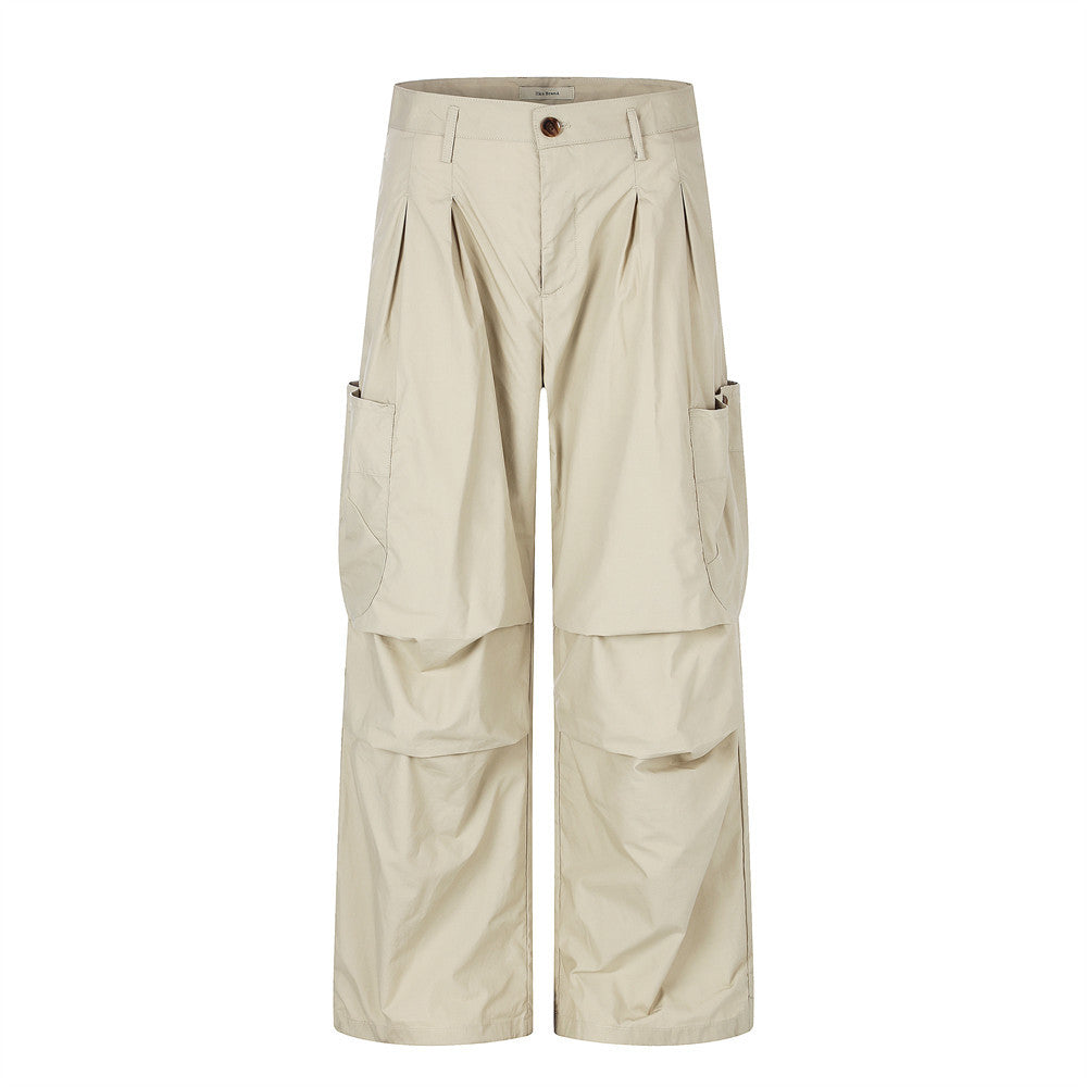 Wide-leg sand beige cargo pants with front pleats, oversized side pockets, and layered knee panel construction