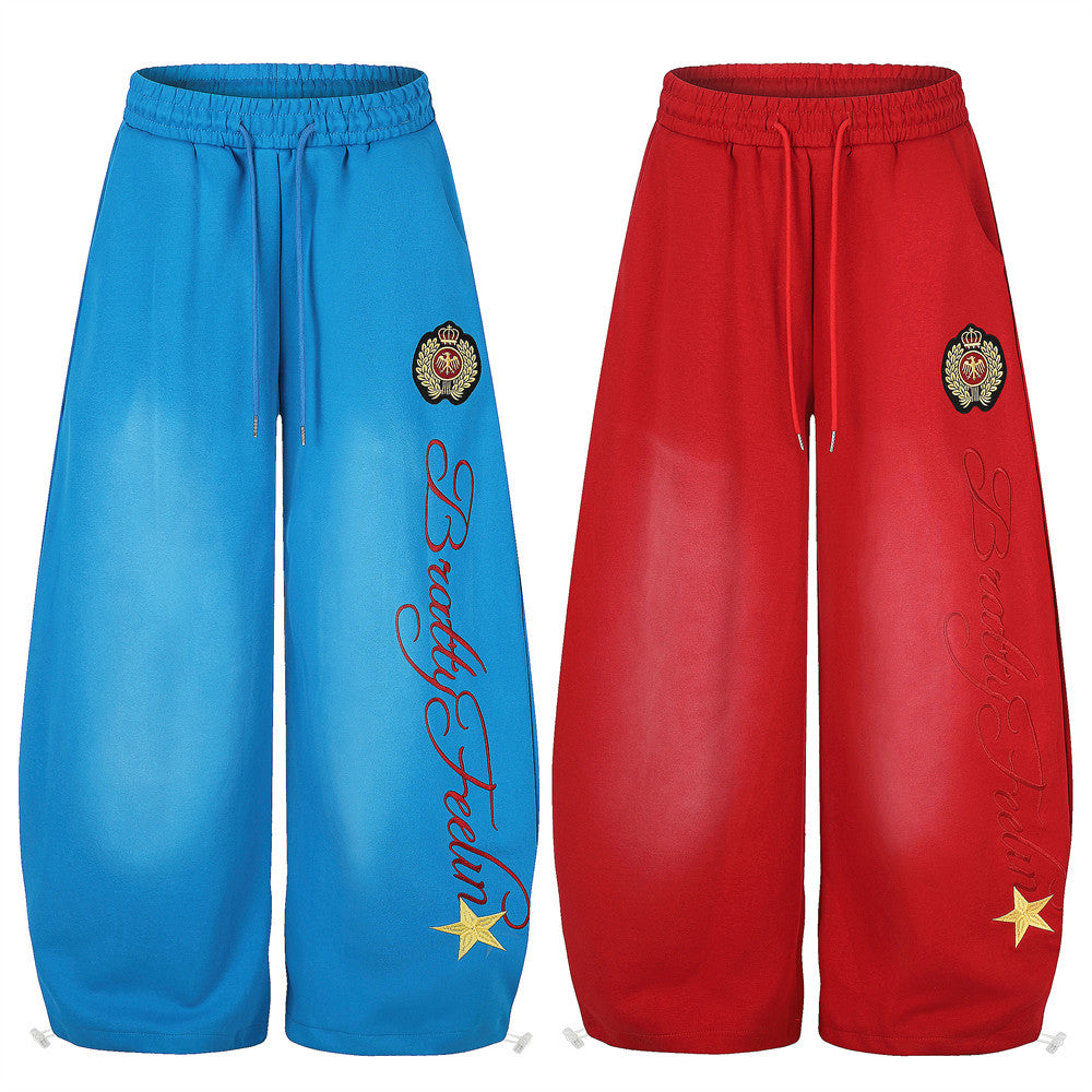 Blue and red wide-leg sweatpants shown front view with embroidered crest and script print