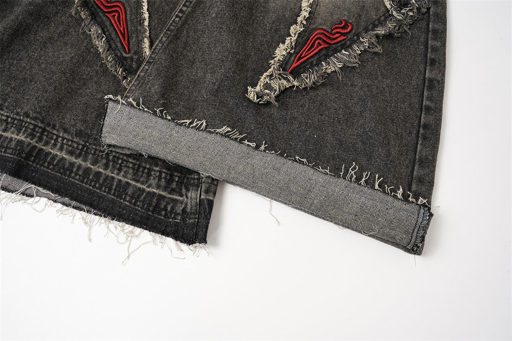 Close-up of the hem on black wide leg jeans with raw-edge finish and folded cuff detail
