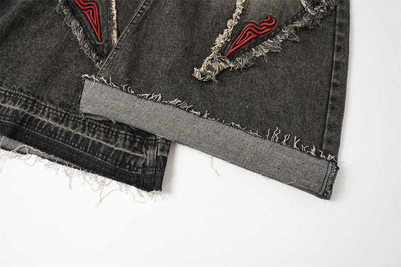 Close-up of the hem on black wide leg jeans with raw-edge finish and folded cuff detail