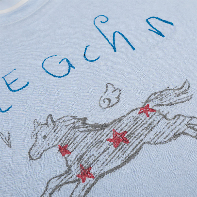 Close-up of front graphic showing running horse and blue handwritten text on light blue tee
