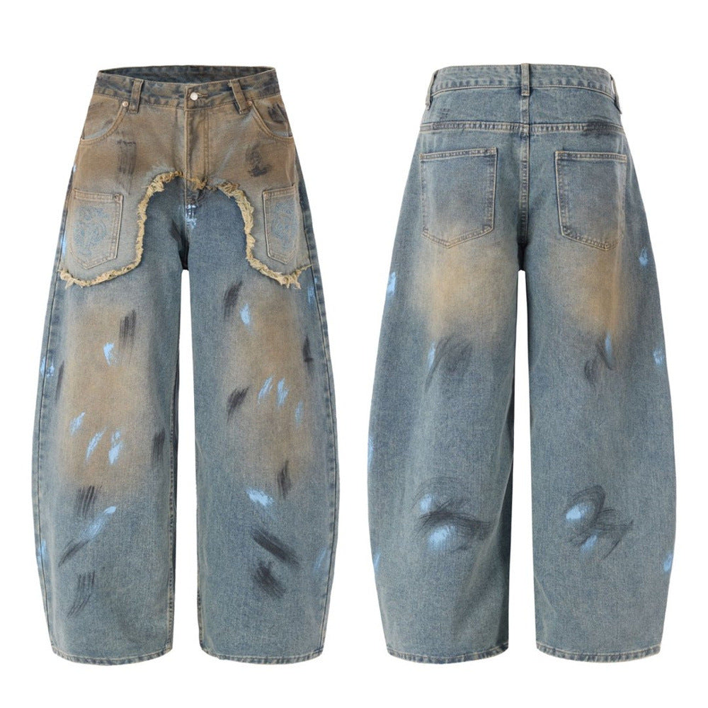 Baggy wide-leg jeans with two-tone patchwork, frayed raw-edge seam, and paint splatter distressed print in vintage blue and e