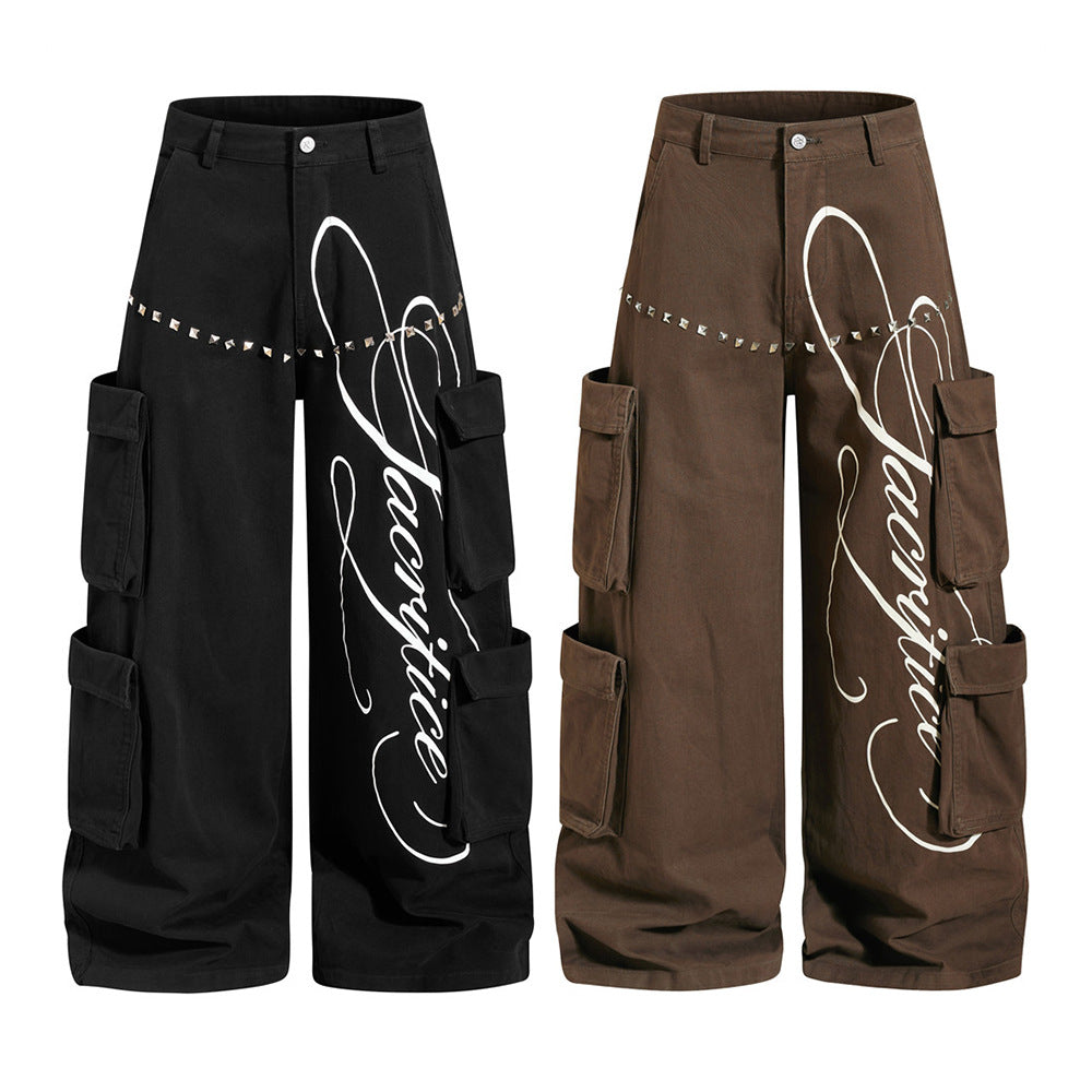 Men's wide-leg black cargo pants with white cursive script print and metal rivet trim across the thigh