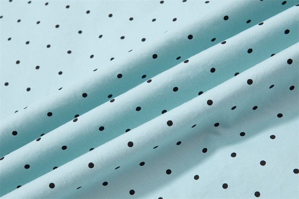 Close-up of light blue fabric with black polka dots laid in folds