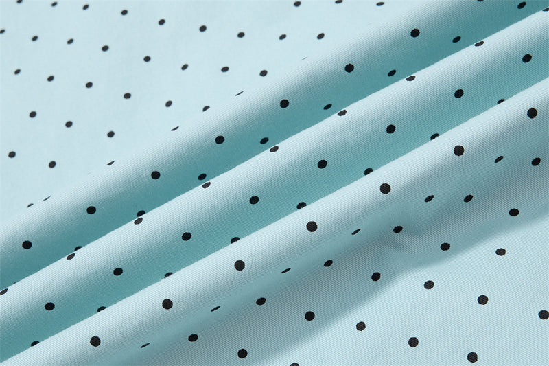 Close-up of light blue fabric with black polka dots laid in folds