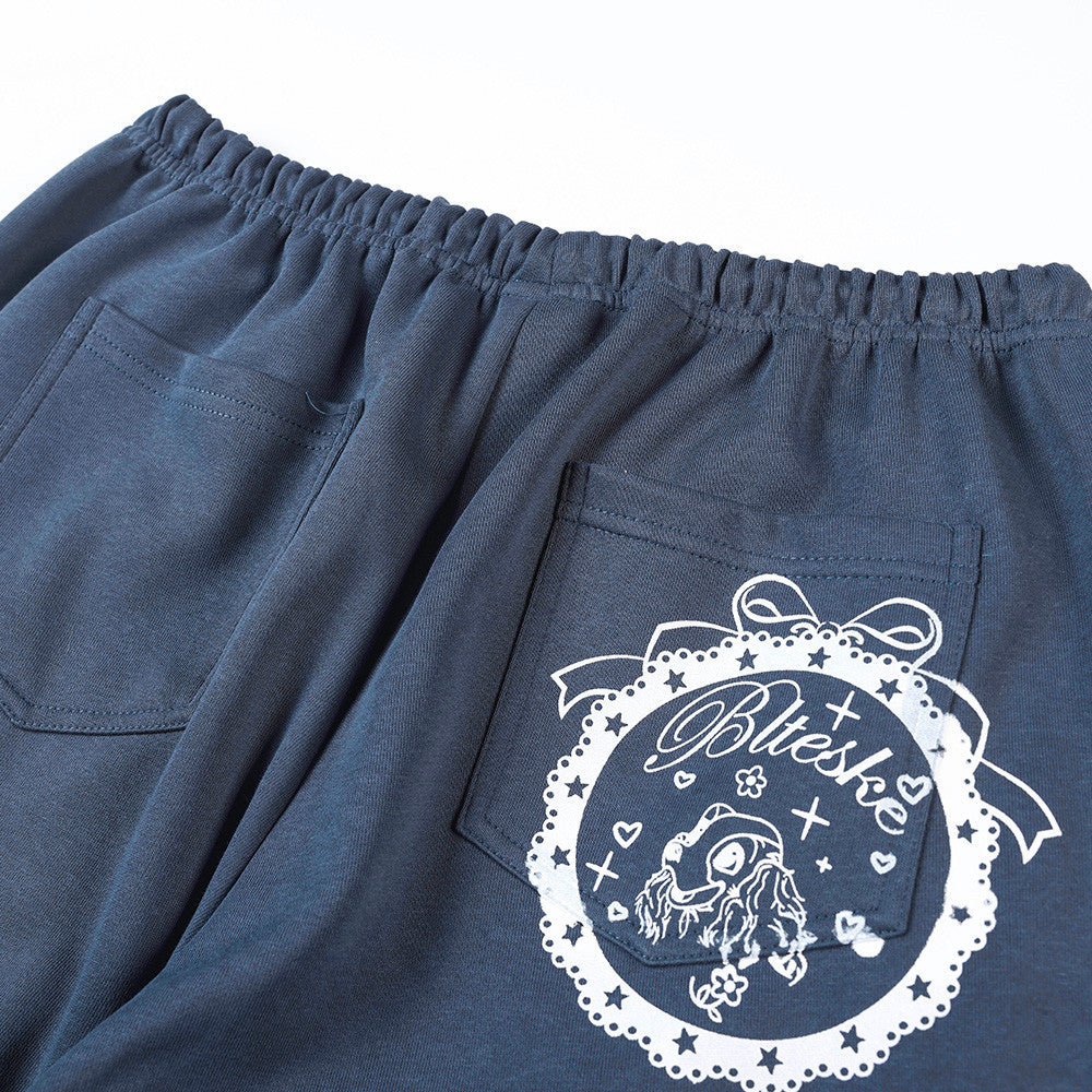 Close-up of back pocket and white circular graphic print on navy track pants