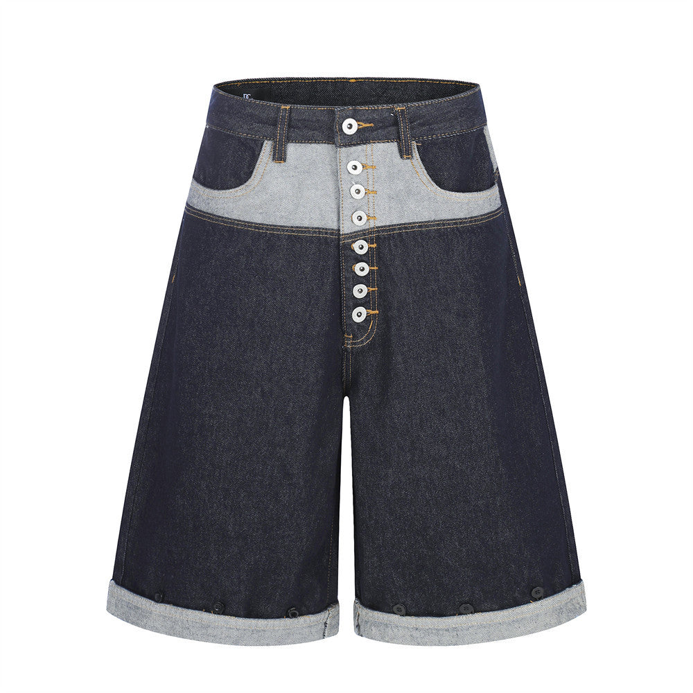 Men's dark indigo contrast patchwork wide-leg denim shorts with exposed button fly and rolled cuff hem, front view