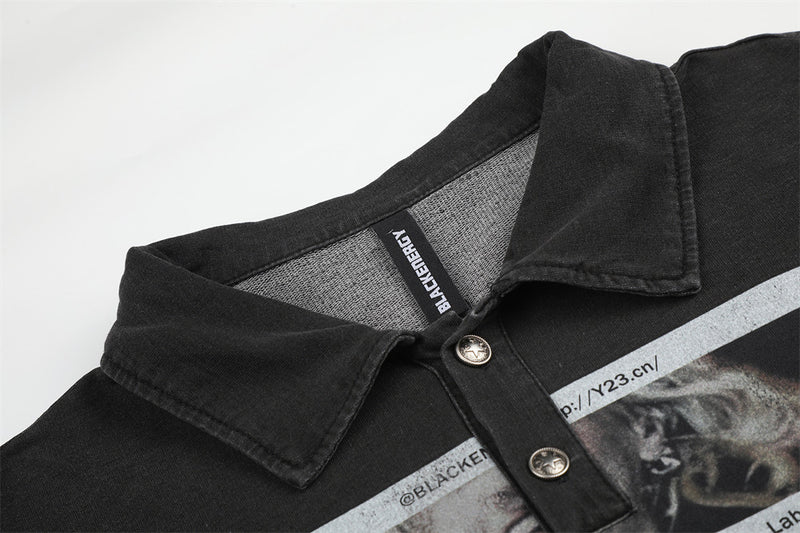 Close-up of black polo collar and button placket with printed graphic underneath