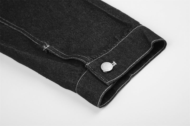 Close-up of black denim jacket cuff with snap button and stitched seam