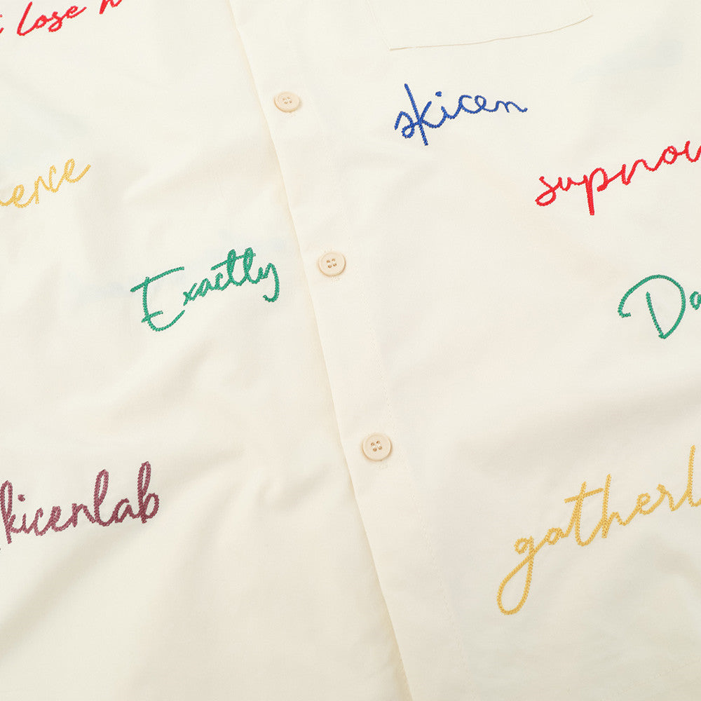 Cream shirt front close-up showing multicolor script embroidery and button placket