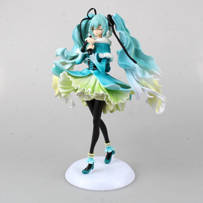 The Hatsune Miku 1/7 Scale 28cm PVC Figure – Elegant Pose with Flowing Hair showcases a stylized character with long turquoise hair and a teal dress, holding a black and teal microphone-like object. Featuring green accents and black stockings, this collectible stands elegantly on its round white base.