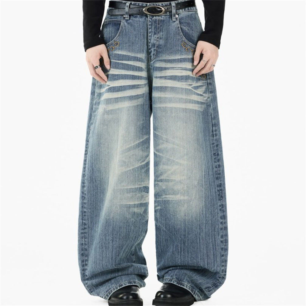Men's light blue baggy wide-leg jeans with vintage horizontal crease wash and gold scroll embroidery at front pocket