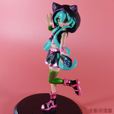 The Hatsune Miku Cat Hoodie 17cm PVC Figure features Miku in a black cat hoodie, green and pink outfit, long turquoise hair, artfully posed with one hand raised while balancing on one foot against a soft pink background.