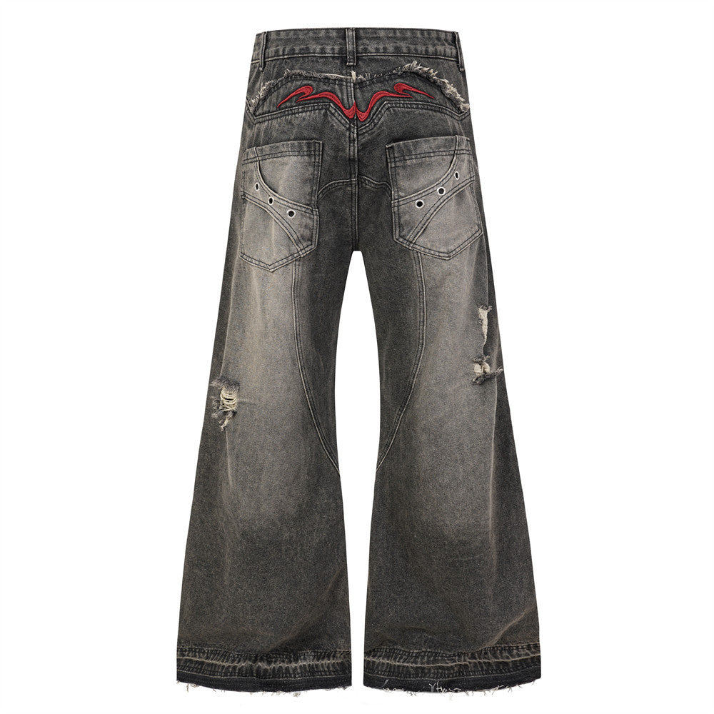 Back view of black wide leg jeans with faded wash, red embroidered yoke, and frayed hems