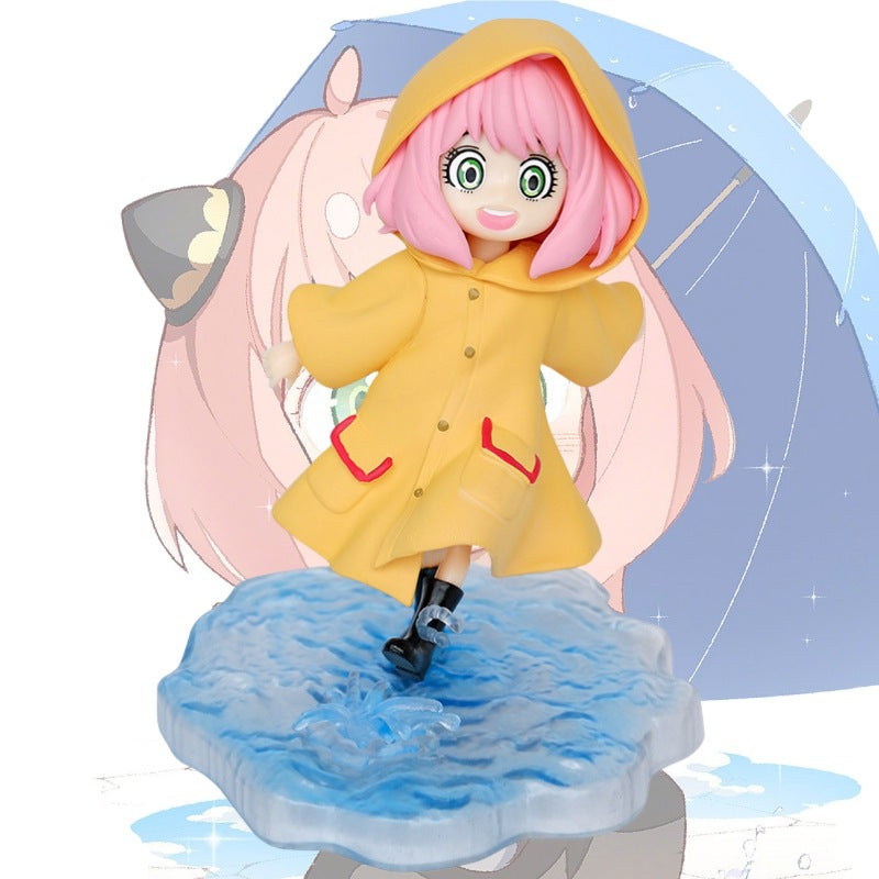 The Anya Forger Yellow Raincoat Figure - Cute PVC Anime Collectible from Spy × Family is chibi-style with pink hair, wide eyes, and an umbrella on a water-like base. The background illustration mirrors this figure&