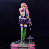 The Kanroji Mitsuri Action Figure from Demon Slayer showcases a character with pink and green hair, in a dark purple outfit and white cape. This 25cm collectible stands on a base inscribed "KANROJI MITSURI," wielding a sword and featuring lime green stockings.