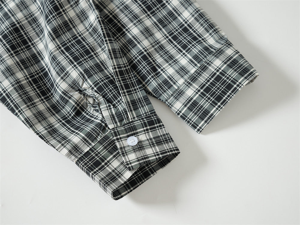 Close-up of black plaid shirt cuff with buttoned long sleeve