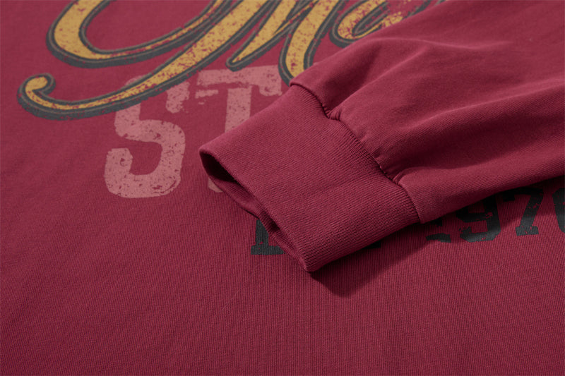 Close-up of burgundy sleeve cuff and front print on long sleeve shirt