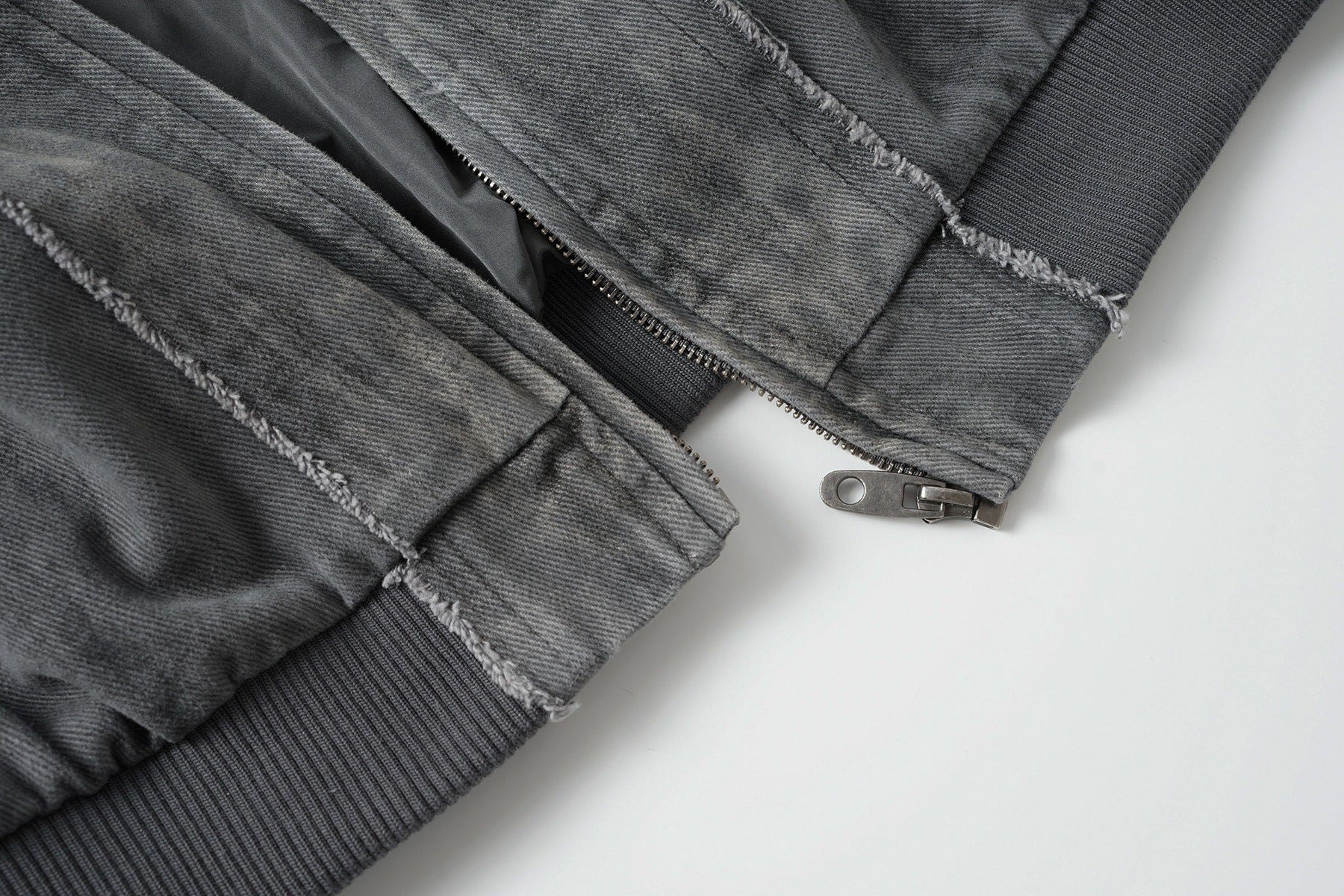 Veste bomber en jean délavé déconstruite à empiècement croisé et coutures effilochées