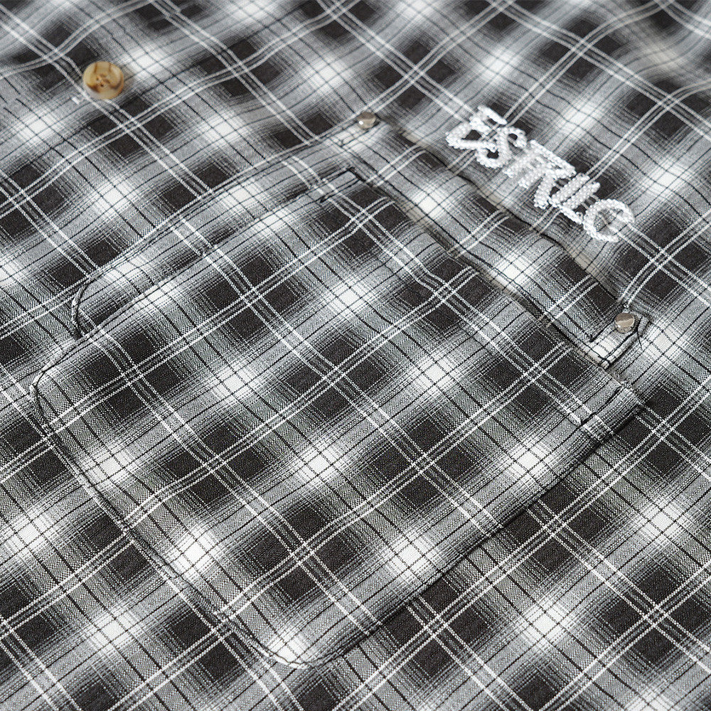 Close-up of black plaid shirt chest pocket and logo detail