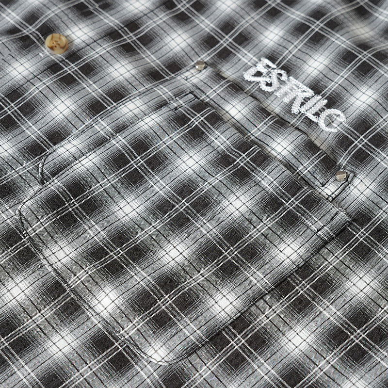 Close-up of black plaid shirt chest pocket and logo detail