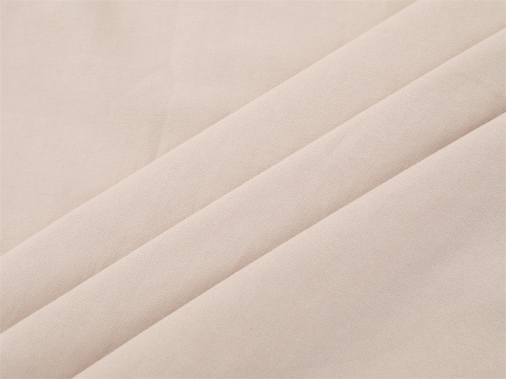 Close-up of beige woven shirt fabric with soft draped folds
