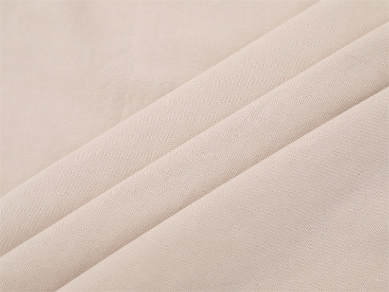 Close-up of beige woven shirt fabric with soft draped folds