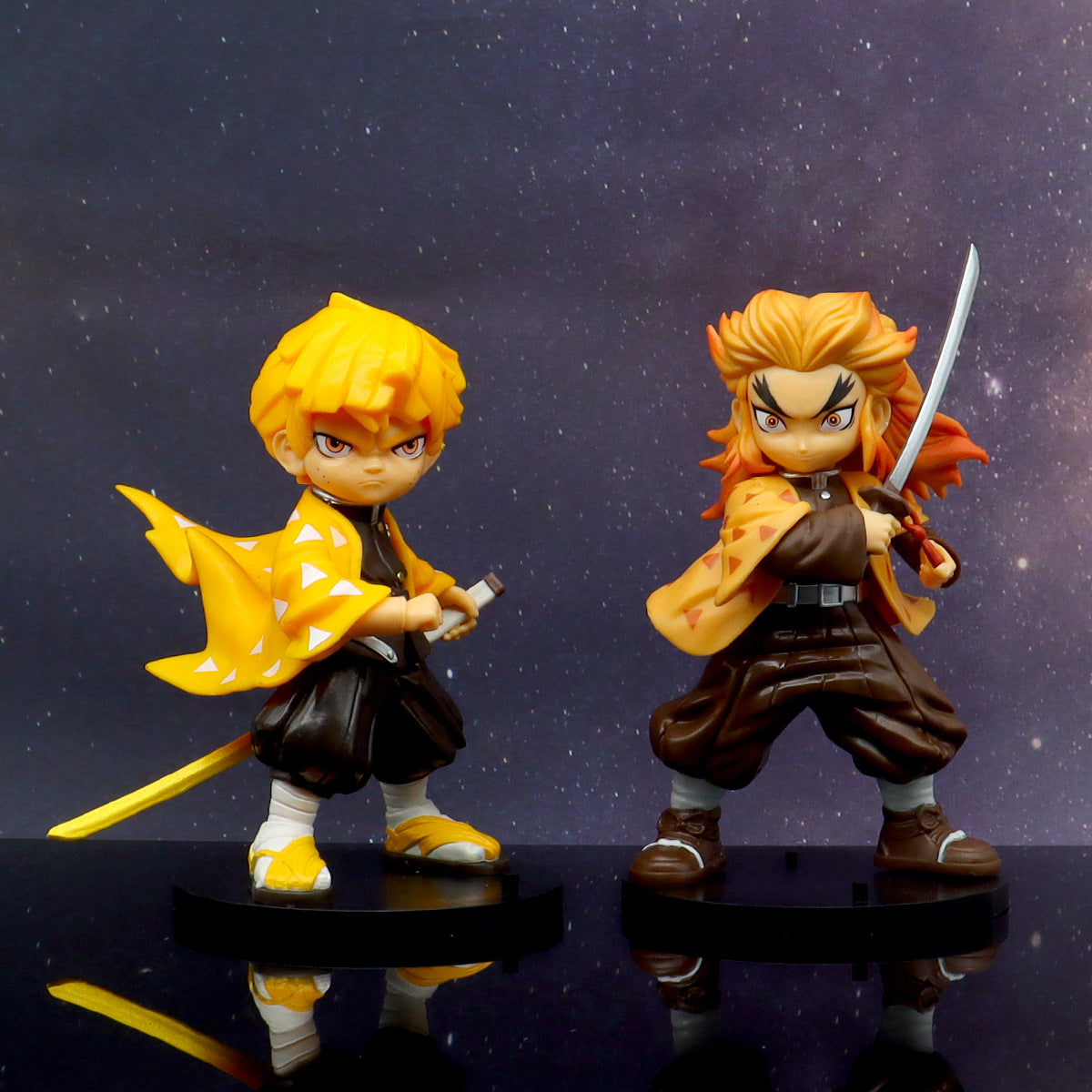 Two high-quality figures from the Demon Slayer 4-Piece Set are displayed against a starry background. Zenitsu, in a yellow cloak, holds a small weapon on the left, while Rengoku, with two-toned hair, wields a sword on the right. Perfect anime gifts, they stand confidently on black bases.