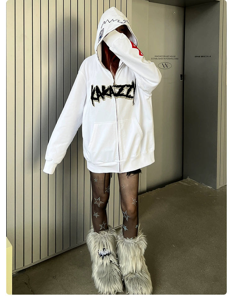 A person in a Berserk Griffith-Inspired Hoodie - 400GSM Oversized White Zip-Up Anime Sweatshirt with black text stands against a wall. Star-patterned tights and furry gray boots complete their look, beloved by Berserk fans. Their face is hidden by the hood.