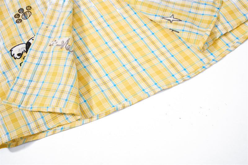 Side view of yellow plaid shirt showing sleeve cuff and embroidered front hem