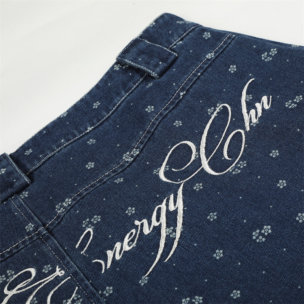 Close-up of white script embroidery across the back waistband on dark blue jeans