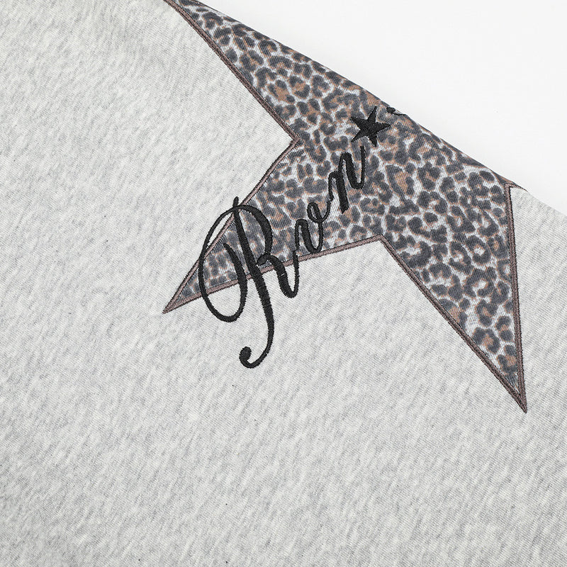 Close-up of leopard print star patch with script detail on gray sweatpants