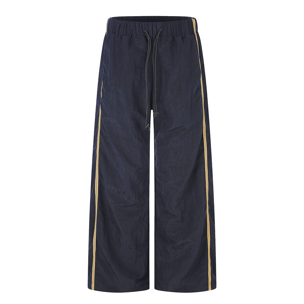 Navy wide-leg track pants with gold zigzag side stripe and drawstring waist, front and back view