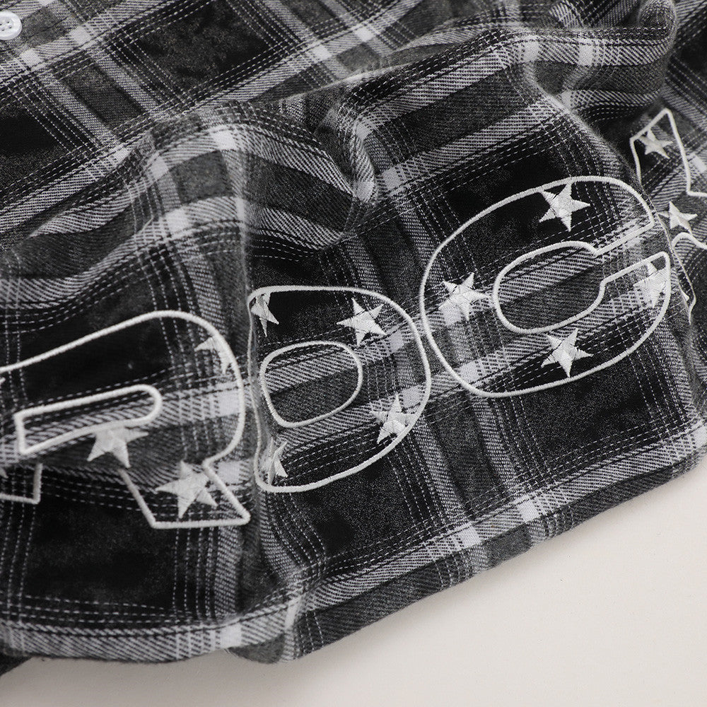 Close-up of sleeve hem on black plaid flannel with large white star graphic