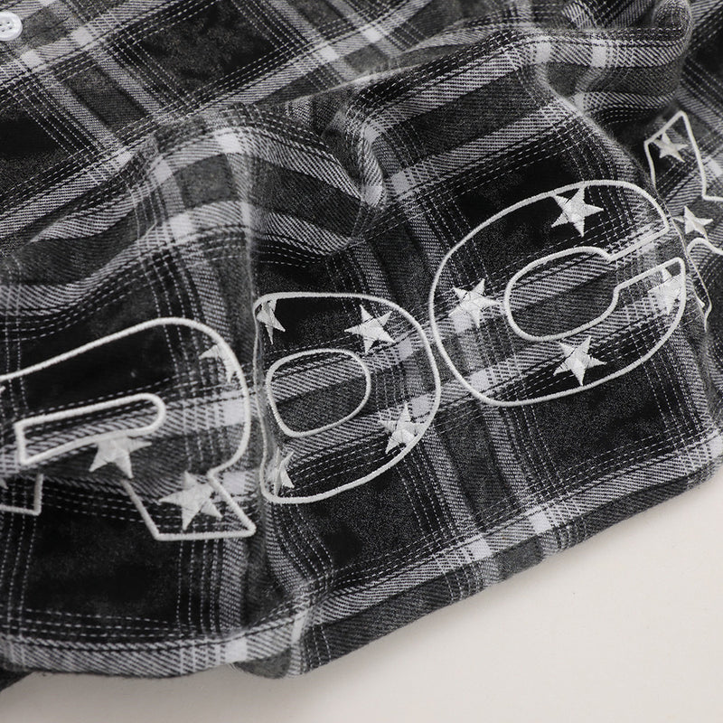 Close-up of sleeve hem on black plaid flannel with large white star graphic