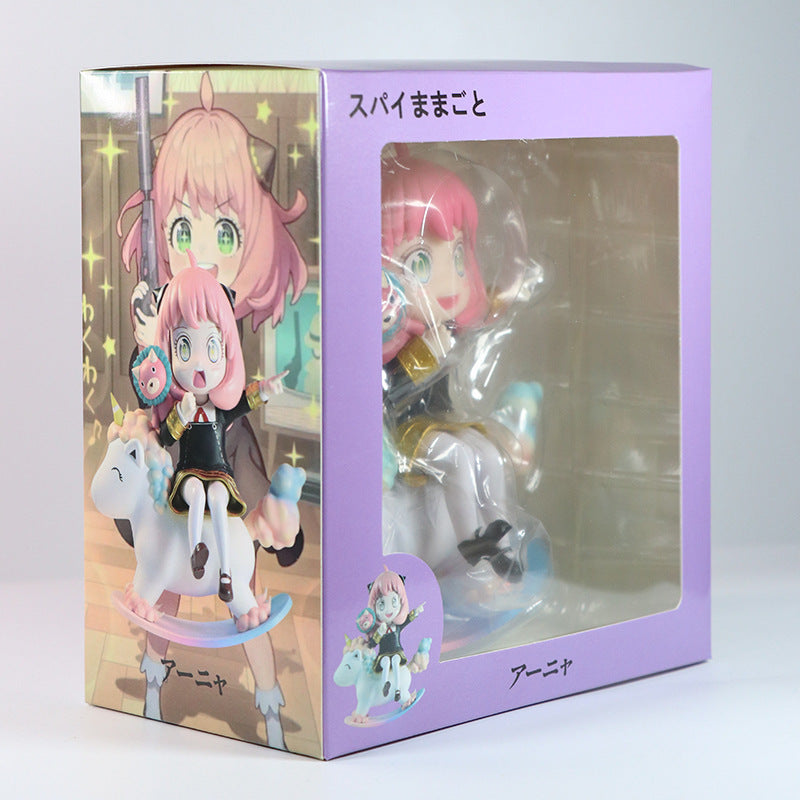 The Spy x Family Anya Forger PVC figure features Anya with pink hair on a unicorn, holding a gadget. Measuring 15 cm, it includes an interchangeable face. The box has a display window and an illustrated depiction of Anya on the side, with Japanese text.