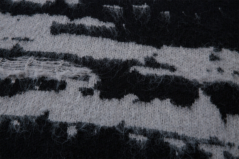 Detailed view of fuzzy black and gray jacquard knit texture with uneven horizontal stripe edges