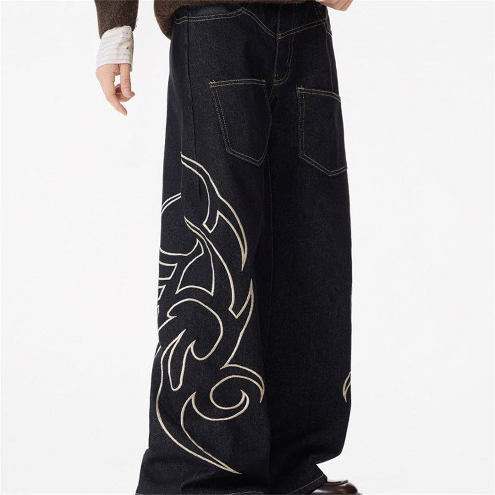 Side view of black baggy jeans with large tribal flame embroidery along the leg