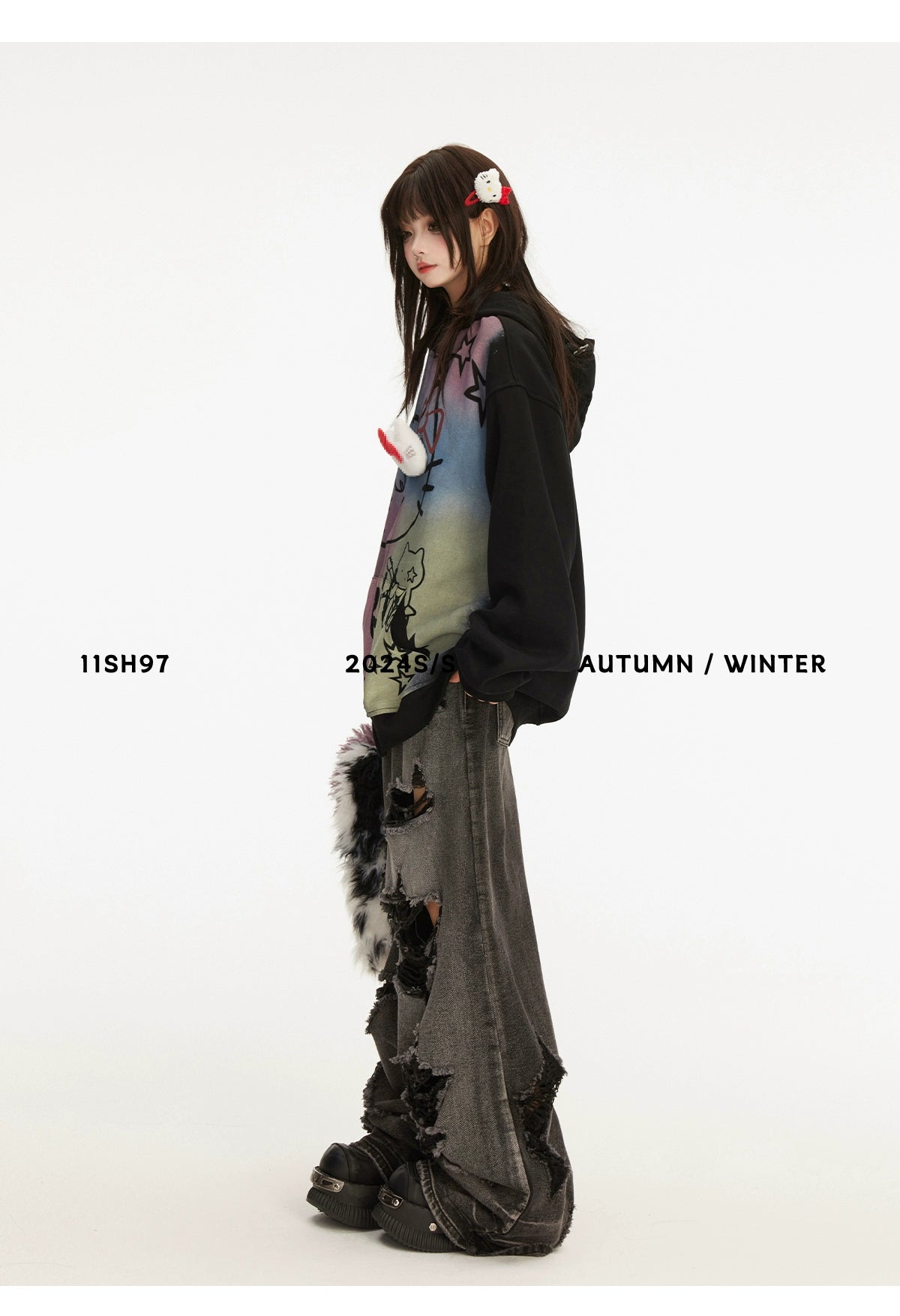 Against a plain backdrop, someone dons a Seakoff Pastel Cat Graffiti Full-Zip Hoodie, showcasing streetwear charm. Paired with distressed wide-leg jeans and dark hair pinned back, they look aside. The image text reads &quot;11SH97 2023 S/S AUTUMN / WINTER.