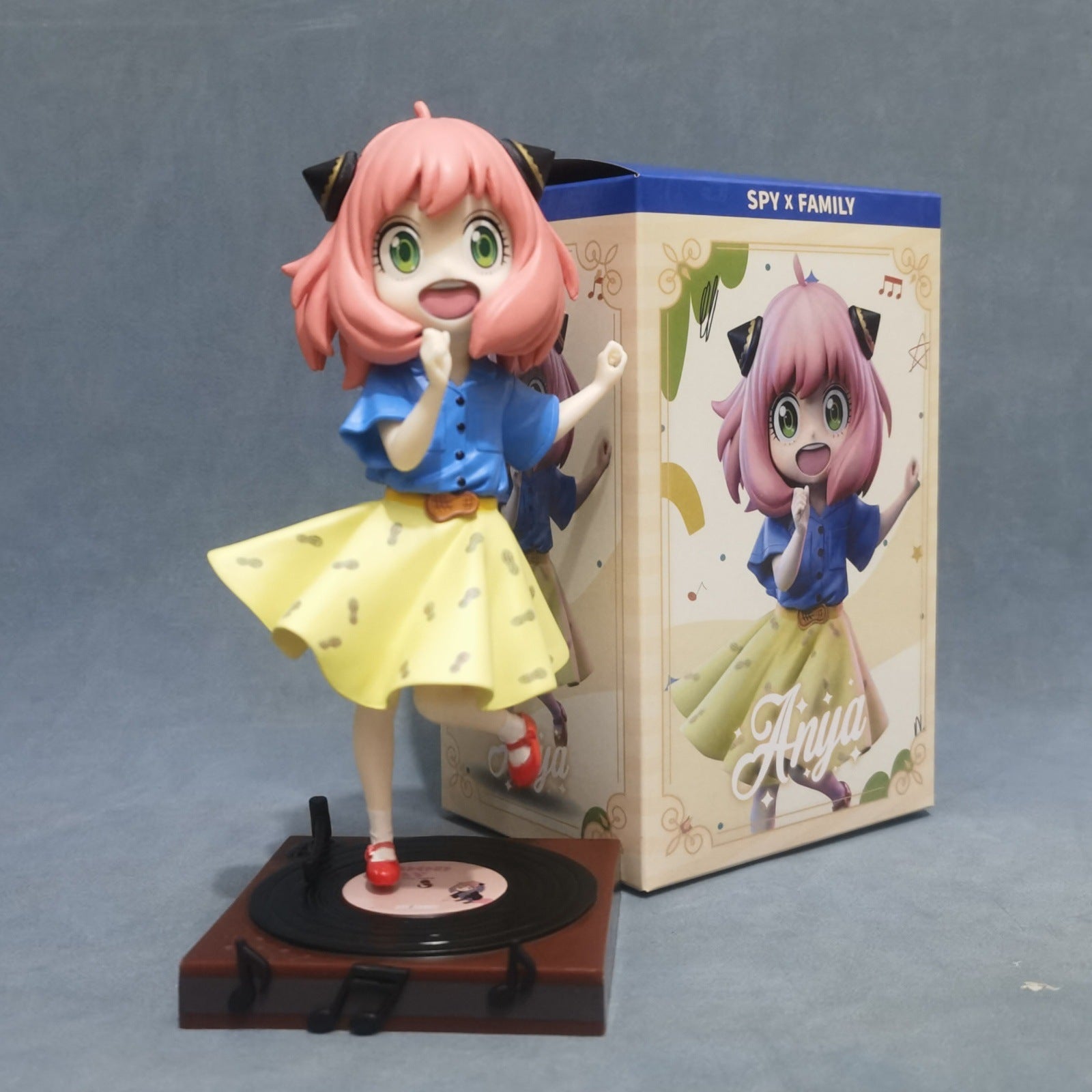 The Seakoff 18cm PVC Anya Forger Dancing Figure from Spy x Family features a cheerful, pink-haired girl in a blue shirt and yellow skirt on a record player platform. The box showcases music notes and &quot;SPY x FAMILY&quot; with &quot;Anya,&quot; making it perfect for any anime figure collection. Limited edition!.