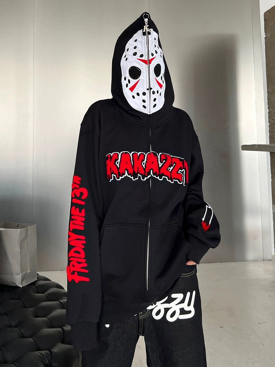 A person dons a Seakoff Friday the 13th Hoodie featuring a Jason mask hood, red &quot;KAKAZY&quot; text on the chest, and &quot;FRIDAY THE 13TH&quot; on the sleeve. They pair it with black pants displaying white text—a must-have for horror movie enthusiasts.