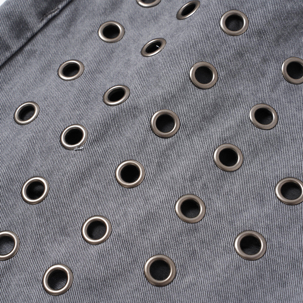 Close-up of grey denim fabric with scattered metal eyelets