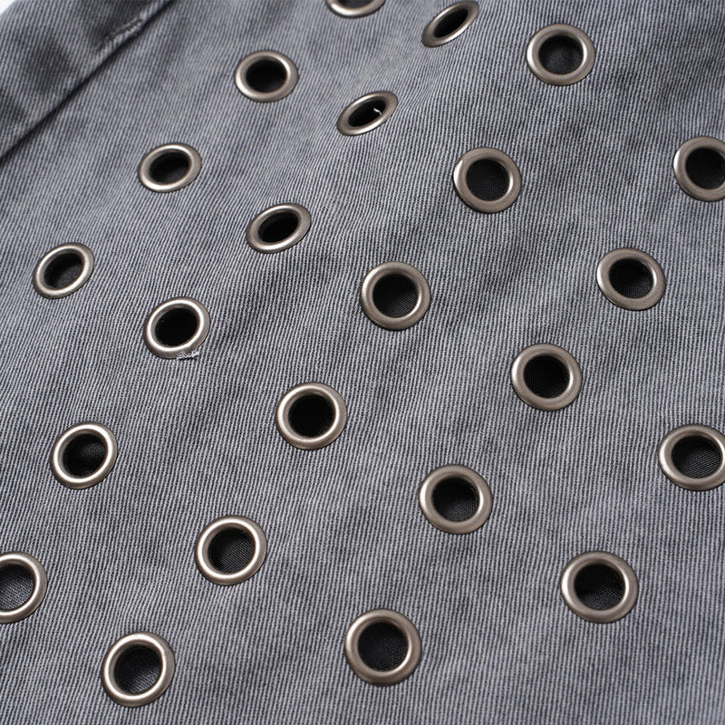 Close-up of grey denim fabric with scattered metal eyelets