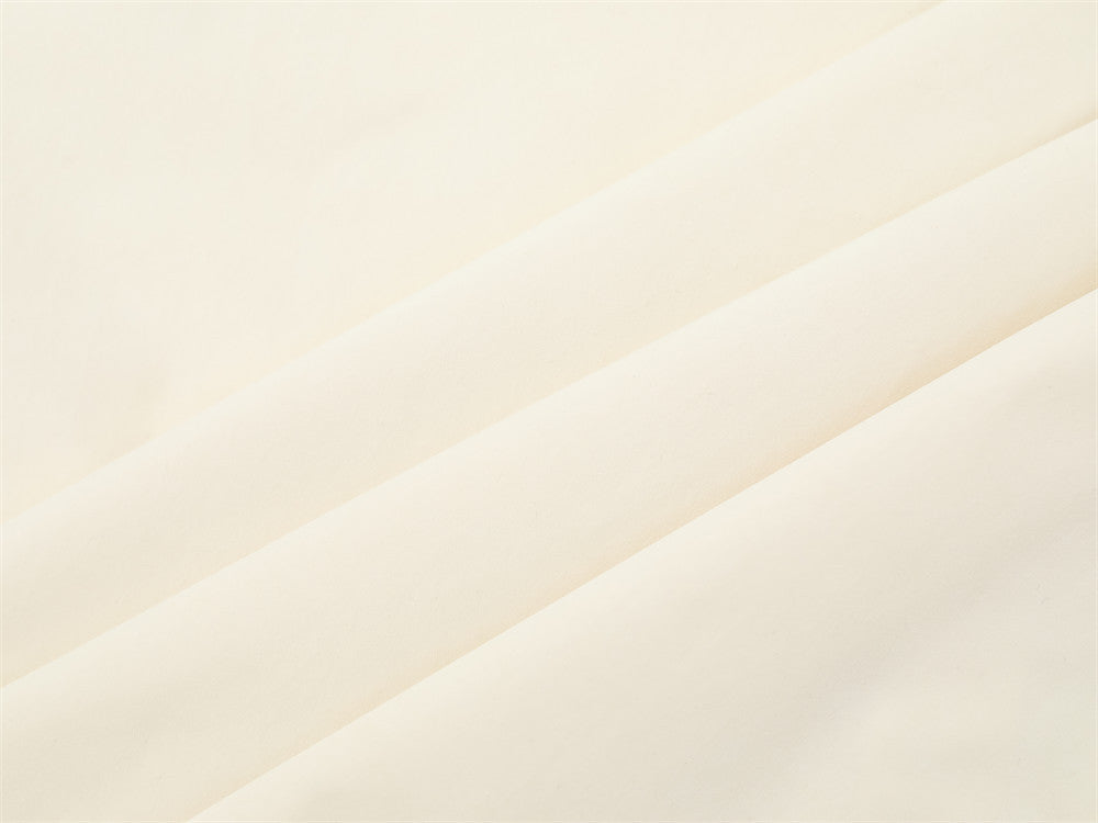 Close-up of cream shirt fabric texture with soft diagonal folds