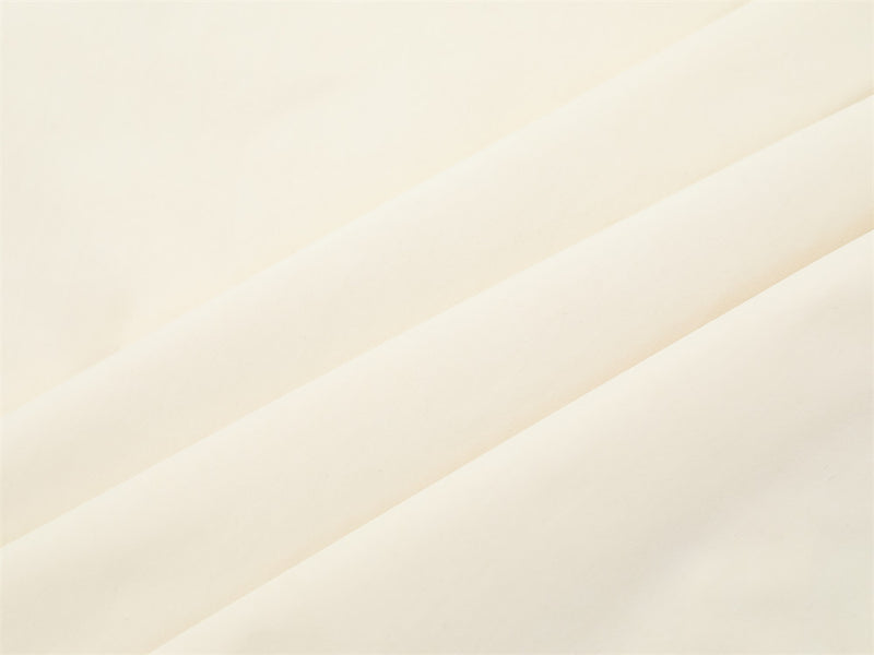 Close-up of cream shirt fabric texture with soft diagonal folds