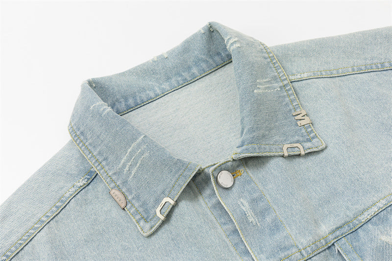 Close-up of the light wash denim jacket collar with stitching, metal buttons, and a small metal tab