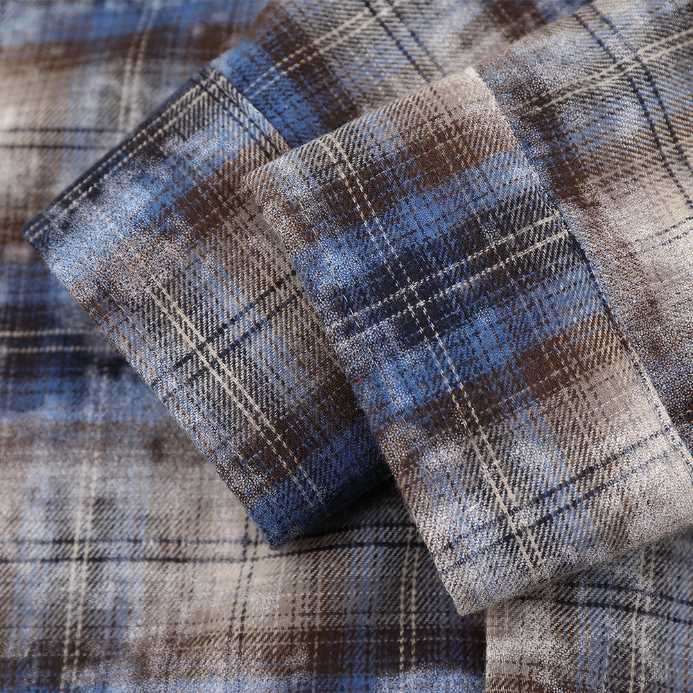 Close-up of cuffed sleeve detail on blue plaid shirt